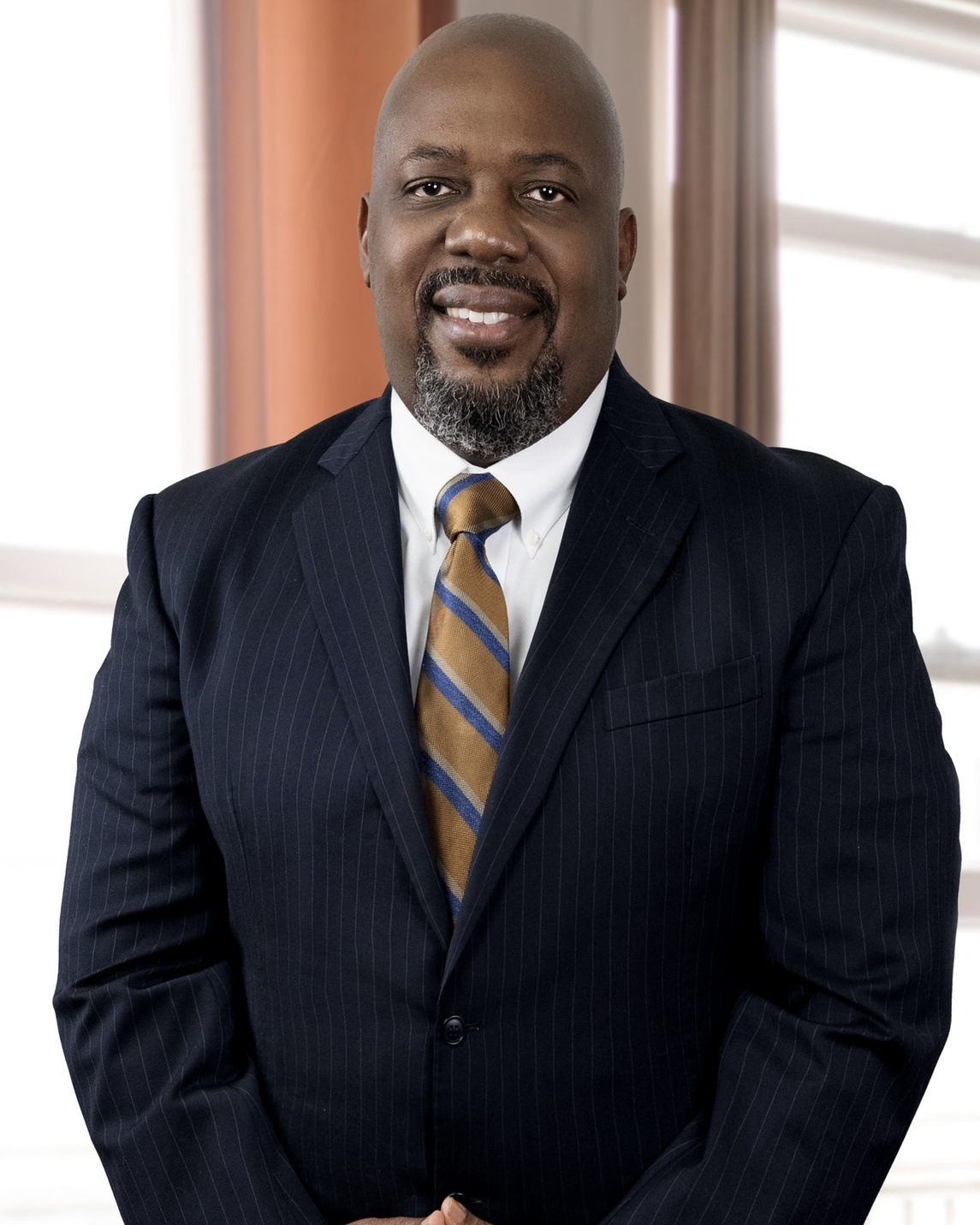 Dion Brinson wearing a navy suit with a gold-and-blue tie